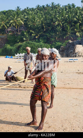 Ländliche Bewohner im täglichen Leben. Den Fischern am Ufer des Ozeans ziehen. Chowara, Kerala, im Südwesten Indiens. Stockfoto