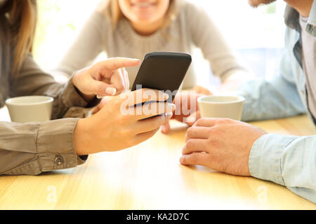 Nahaufnahme von den Händen der drei Freunde in einem smart phone in einer Bar Tisch oder Home Stockfoto