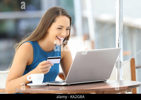 Single Frau Bezahlung Online mit Kreditkarte und einen Laptop in einer Bar auf der Terrasse sitzen Stockfoto