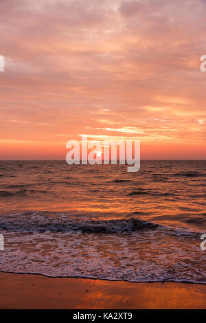 England, Broadstairs. Sonnenaufgang über dem Meer mit Schicht von Wolke über den Himmel reflektieren das rote Licht. Die Wellen am Strand im Vordergrund. Stockfoto