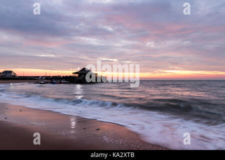 England, Broadstairs. Sonnenaufgang über dem Meer mit Broadstairs Hafen im Vordergrund. Die Wellen am Strand im Vordergrund. Stockfoto