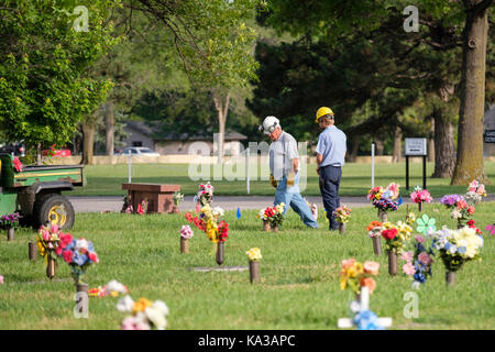 Zwei Friedhof Mitarbeiter Spaziergang zwischen Blumenschmuck zu Ehren der Toten am Memorial Day in einem Friedhof in Wichita, Kansas, USA. Stockfoto