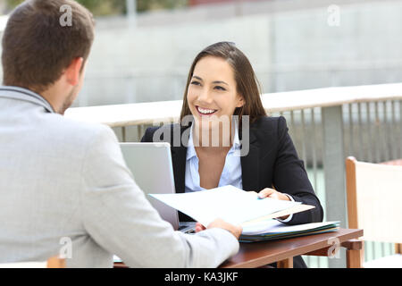 Zwei Führungskräfte arbeiten Teilen informiert in einer Bar auf der Terrasse sitzen Stockfoto