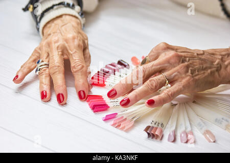 Alte Frau gepflegte Hände mit Ringen. Senior womans Hände mit rotem Nagellack tragen Ringe. Conept des Reichtums und aristokratismus. Stockfoto