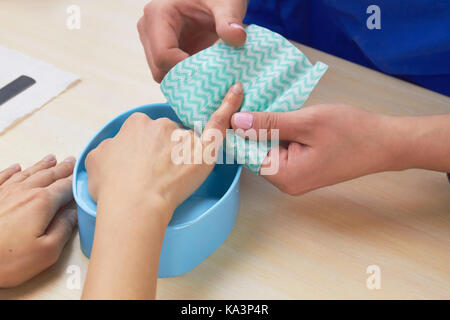 Frau Hände empfangen Maniküre. Kosmetikerin macht spa Verfahren für Kunden die Hände. Nagelstudio wischen finger Kunden vor der Maniküre. Stockfoto