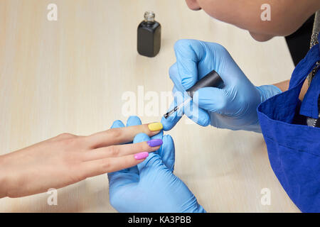 Frau Nagel Maniküre im Schönheitssalon. Maniküre lackieren Nägel Client mit verschiedenen Farben des Sommers. Junge Frau im Nagelstudio. Stockfoto