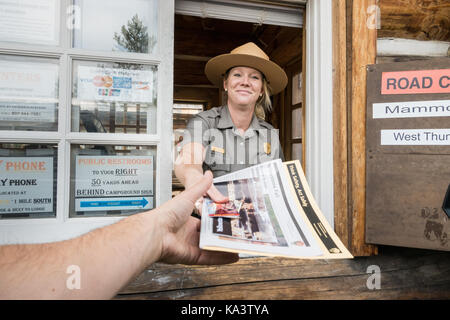 Sehr einladend weiblichen Park Ranger, am Eingang stand, Übergabe in Karte und Park Informationen zum Yellowstone National Park, USA mit einem Lächeln Stockfoto