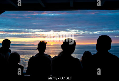 Die Leute bewundern, ein dramatischer Sonnenuntergang auf dem Wasser, der Straße von Georgia, während an Bord eines BC-Fähre zum Festland reisen Vancouver. Stockfoto