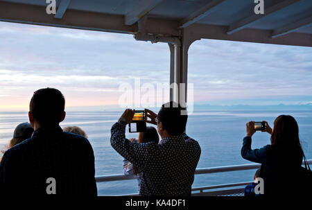 Passagiere, die mit ihren iphones und Mobiltelefonen Fotos von einem BC-Fährschiff machen, das auf der Straße von Georgia unterwegs ist Stockfoto