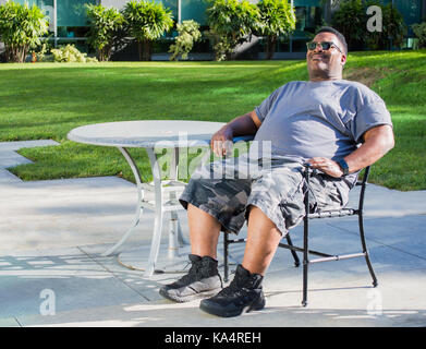 Schwarz im mittleren Alter Mann an einem Tisch draußen sitzen Stockfoto