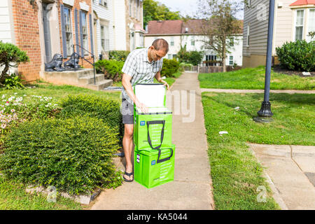 Fairfax, USA - 12. September 2017: Amazon Frisch isolierte Lebensmittel-lieferservice Taschen, Taschen auf der Vorderseite Home Haus Veranda closeup, junger Mann, Sie zu öffnen. Stockfoto