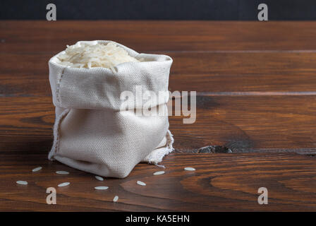 Sac von Reis auf einem Holztisch mit einem dunklen Hintergrund Stockfoto