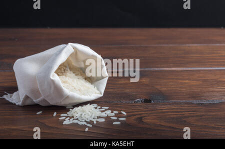 Sac von Reis auf einem Holztisch mit einem dunklen Hintergrund Stockfoto