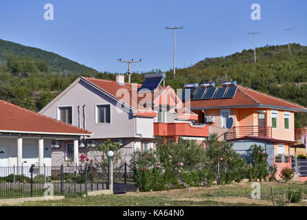 Sonnenkollektoren auf den Dächern der Neuen Häuser im Dorf und klaren Himmel Stockfoto