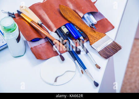 Close-up braun Ledertasche mit Pinsel in verschiedenen Größen auf einem weißen Tabelle, Ansicht von oben Stockfoto