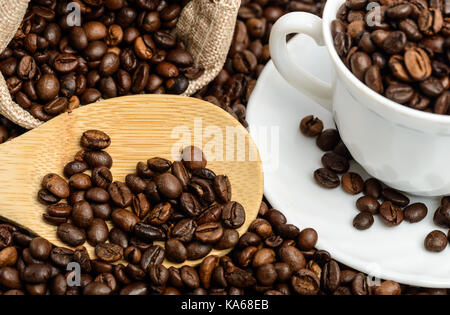 Kaffeebohnen in Jute Sack mit Holzlöffel und Espresso Tasse. Ansicht von oben Stockfoto