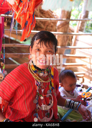 Closeup Porträt der jungen Frau mit einem Kind Akha heidnischen Stamm. Junge Frau Verkauf von handgemachten Textil in Stamm Dorf. Stockfoto