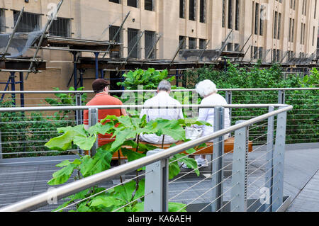 Touristen sitzen auf einer Bank auf der High Line Greenway in Manhattan, New York City, USA. Stockfoto