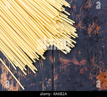 Rohe spaghetti Pasta auf schwarzen alten hölzernen Tisch verstreut, Ansicht von oben Stockfoto