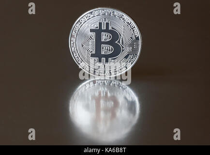 Die Silbermünze bitcoin liegt oder steht am Rande auf einem dunklen Hintergrund, Spiegel reflektiert. Das Konzept der crypto Währungen. Stockfoto