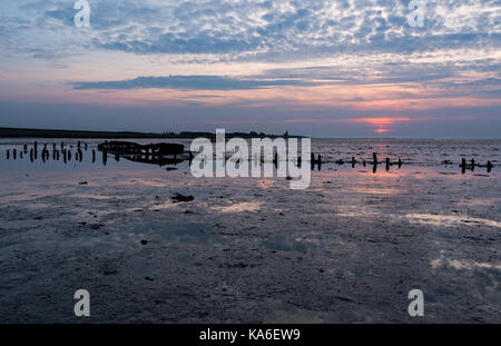 Alte havarierten Boot mit Sonnenuntergang am Wattenmeer, Nordsee Holland Stockfoto