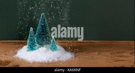 Über miniatur Weihnachtsbaum auf einem Holztisch Schneefall Stockfoto
