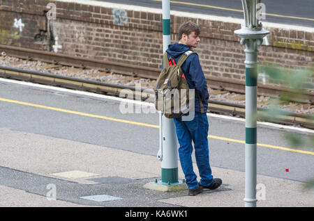 Mann stehend auf einem Bahnsteig auf den Zug an einer britischen Bahnhof in England, Großbritannien. Stockfoto