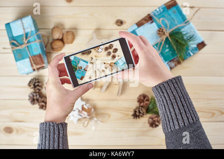 Die frau Hände unter Foto von Weihnachtsschmuck und Geschenke von Smartphone Stockfoto