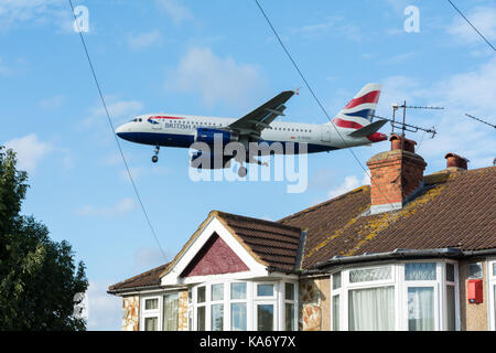 Ein tief fliegenden British Airways Flugzeug in das Land über Myrtle Avenue am Flughafen Heathrow, London, Großbritannien Stockfoto