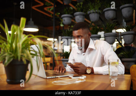Afrikanischer Mann im Internet Shop mit Karte und Laptop shoping. Stockfoto