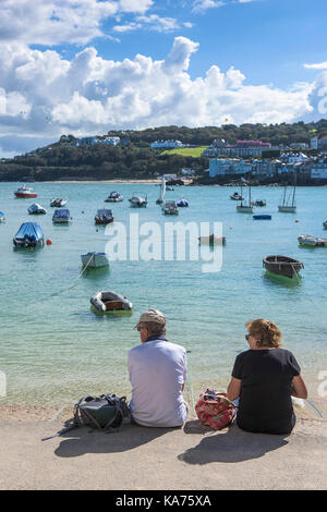 St Ives - Urlauber entspannen am Kai und genießen den Blick über den Hafen von St Ives in Cornwall. Stockfoto