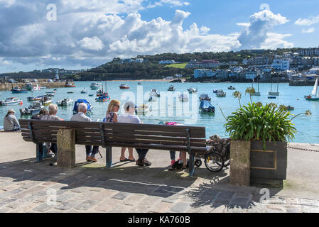 St Ives - Urlauber entspannen am Kai und genießen den Blick über den Hafen von St Ives in Cornwall. Stockfoto