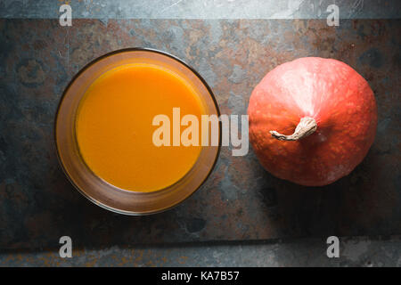 Kürbissuppe und orange Kürbis auf grauem Schiefer horizontal Stockfoto