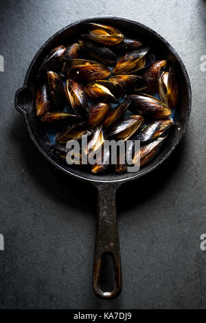 Muscheln gedämpft auf einer gusseisernen Pfanne vertikale Pan Stockfoto