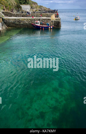 Polperro Hafenmauer mit angelegten Boot und touristische Boot verlassen grün blau Meer unten Cornwall GROSSBRITANNIEN Stockfoto