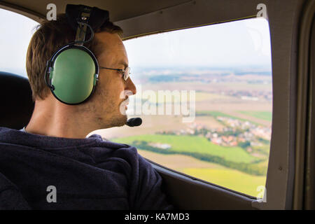 Porträt der jungen Erwachsenen sitzen in privaten Flugzeug und Fenster Stockfoto