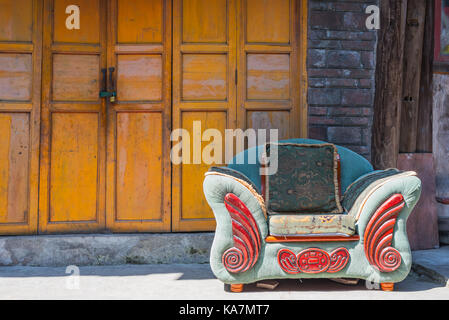Abandonned couch in einem chinesischen Dorf vor einem gelben Tür Stockfoto