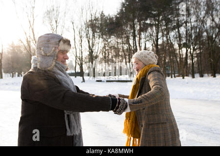 Älteres Paar im sonnigen Winter Natur Eiskunstlauf. Stockfoto