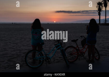 Zwei Radfahrer sehen Sie einen Sonnenuntergang am Venice Beach, Los Angeles, mit Blick auf den Pazifischen Ozean Stockfoto