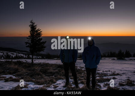 Zwei Wanderer während eines Winters Sonnenaufgang in den Bergen mit Abblendlicht eingeschaltet Posing Stockfoto