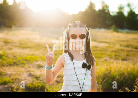 Kleines Mädchen in Sonnenbrillen Musik hören Stockfoto