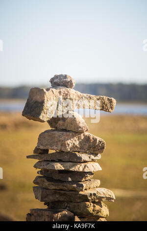 Sonnige Auenlandschaft eines ausgetrockneten Flussbett und Felsen. Stein balancing Konstruktionen in der Nähe des Flusses. Felsige Flusslandschaft. Stockfoto