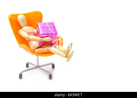 Hölzerne Puppe holding Geschenk sitzen auf Stuhl Stockfoto