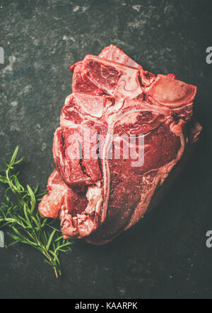 Frisches rohes Rindfleisch T-Bone Steaks mit Rosmarin, schwarzer Hintergrund Stockfoto