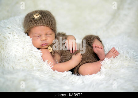 Neugeborenes Baby schläft mit einem Spielzeug niedlich, Teddybären um ihn herum Stockfoto