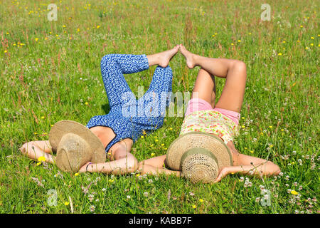 Zwei junge Frauen mit Hüten in grünen Weide liegend Stockfoto