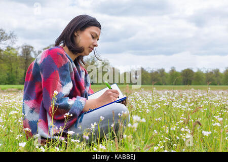 Kolumbianische Frau schreibt in Weide mit Frühling Blumen Stockfoto