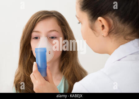 Junge Ärztin mit Inhaler Maske auf Mädchen Stockfoto