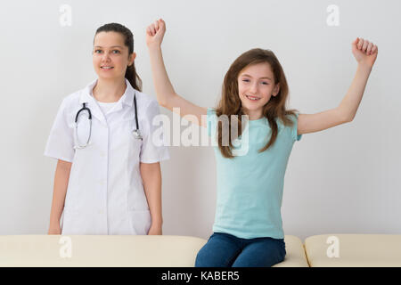 Glückliches Kind sitzt auf dem Bett neben Ärztin im Krankenhaus Stockfoto