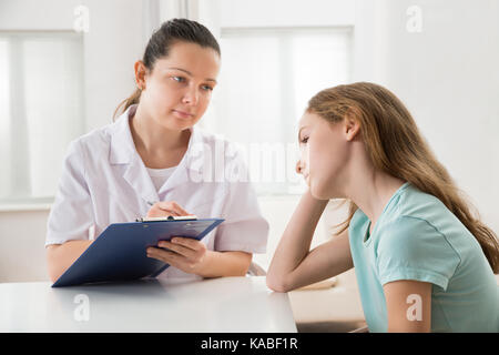 Ärztin tröstend Gedrückt am Tisch sitzenden Patienten Stockfoto